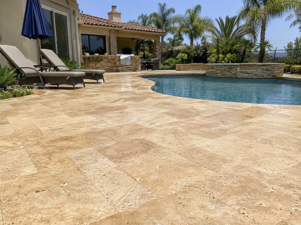 Travertine pool deck at a San Diego property with stone paving around the water